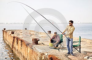 Happy friends with fishing rods on pier