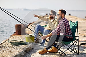 Happy friends with fishing rods on pier