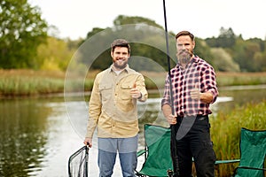 Happy friends with fishing rods showing thumbs up