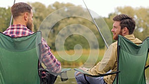 Happy friends fishing and talking on lake