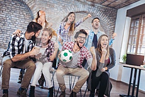 Happy friends or football fans watching soccer on tv