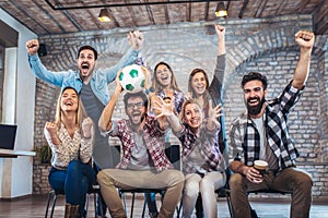 Happy friends or football fans watching soccer on tv and celebrating victory