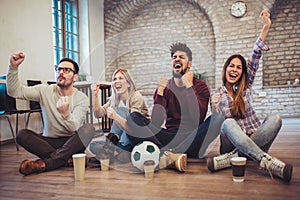 Happy friends or football fans watching soccer on tv and celebrating victory