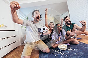 Happy friends or football fans watching soccer on tv and celebrating victory