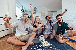 Happy friends or football fans watching soccer on tv and celebrating victory