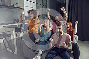 Happy friends of football fans watching soccer on tv and celebrating victory.