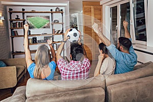 Happy friends or football fans watching soccer on tv and celebrating victory at home.