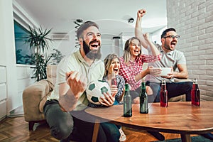 Happy friends or football fans watching soccer on tv