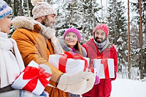 Happy friends with gift boxes in winter forest