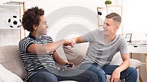 Happy friends giving fists bump while playing video game