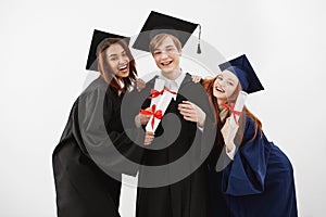 Happy friends graduates smiling holding diplomas looking at camera over white background.