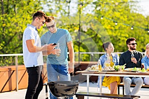 Happy friends grilling at bbq party on rooftop