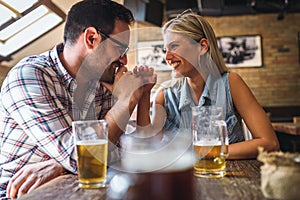 Happy friends having fun at bar - Young trendy couple drinking beer and laughing together