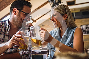 Happy friends having fun at bar - Young trendy couple drinking beer and laughing together