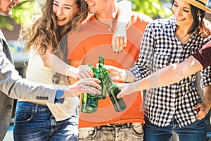 Happy friends group drinking and toasting bottled beer on sunny day outdoors - Friendship concept with young people millennials