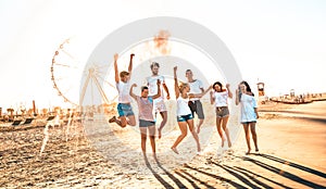 Happy friends group having fun at ferris wheel seaside - Summer vacations friendship concept with millenial guys and girls