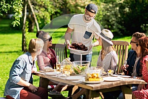 Happy friends having dinner at summer garden party