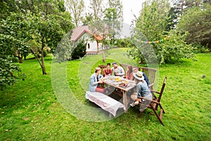 Happy friends having dinner at summer garden party