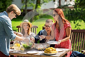 Happy friends having dinner at summer garden party