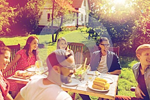 Happy friends having dinner at summer garden party