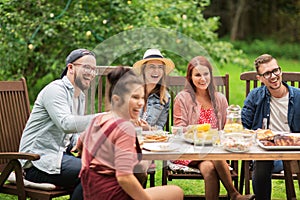 Happy friends having dinner at summer garden party