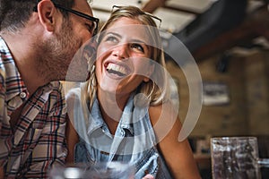 Happy friends having fun at bar - Young trendy couple drinking beer and laughing together