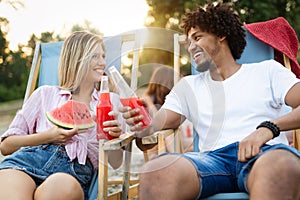 Happy friends having fun on the beach and eating watermelon.