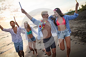 Happy friends having fun beach party outdoor with fireworks