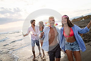 Happy friends having fun beach party outdoor with fireworks