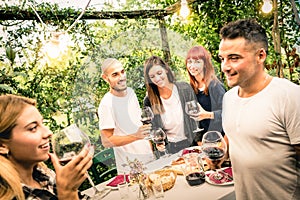 Happy friends having fun drinking red wine at backyard garden