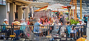 Happy friends having fun drinking wine at street food restaurant. People eating local plate at outdoor restaurant