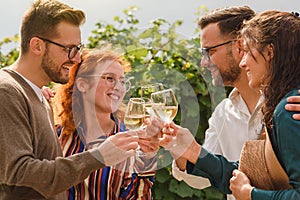 Happy friends having fun drinking wine at vineyard