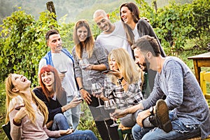 Happy friends having fun outdoor - Young people drinking red wine at winery vineyard