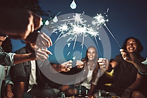 Happy friends having fun outdoors. Cheerful people enjoying party with sparklers in park