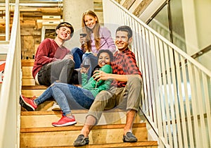 Happy friends having fun toasting red wine restaurant - Young people sitting in wood pub stairs drinking and laughing - Friendship