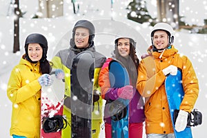 Happy friends in helmets with snowboards