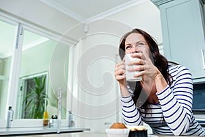 White ceramic mug steaming on kitchen island, with muffin and cupcake near bright window
