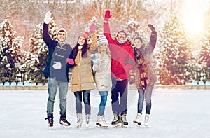 Happy friends ice skating on rink outdoors