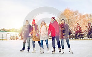 Happy friends ice skating on rink outdoors