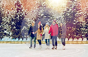 Happy friends ice skating on rink outdoors