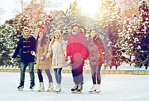 Happy friends ice skating on rink outdoors