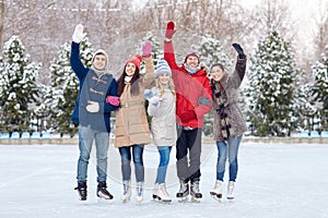 Happy friends ice skating on rink outdoors