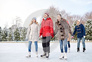 Happy friends ice skating on rink outdoors