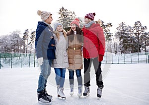 Happy friends ice skating on rink outdoors