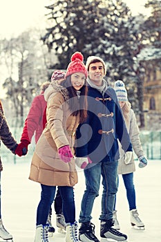 Happy friends ice skating on rink outdoors