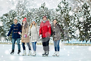 Happy friends ice skating on rink outdoors