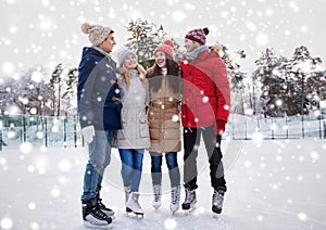 Happy friends ice skating on rink outdoors