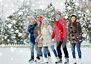 Happy friends ice skating on rink outdoors