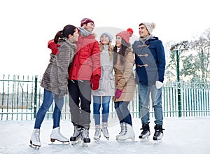 Happy friends ice skating on rink outdoors