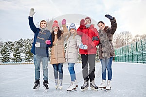 Happy friends ice skating on rink outdoors